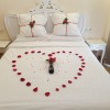 Cama decorada en plan romántico con pétalos naturales preservados, rosas atrificiales y corazoncitos de tela