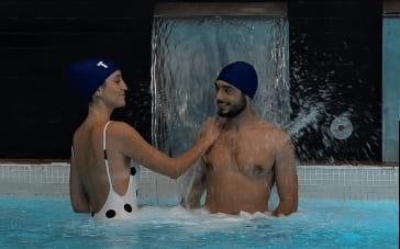 Disfrutando en pareja debajo de la cascada en la piscina activa de Tyris Spa&Fitness